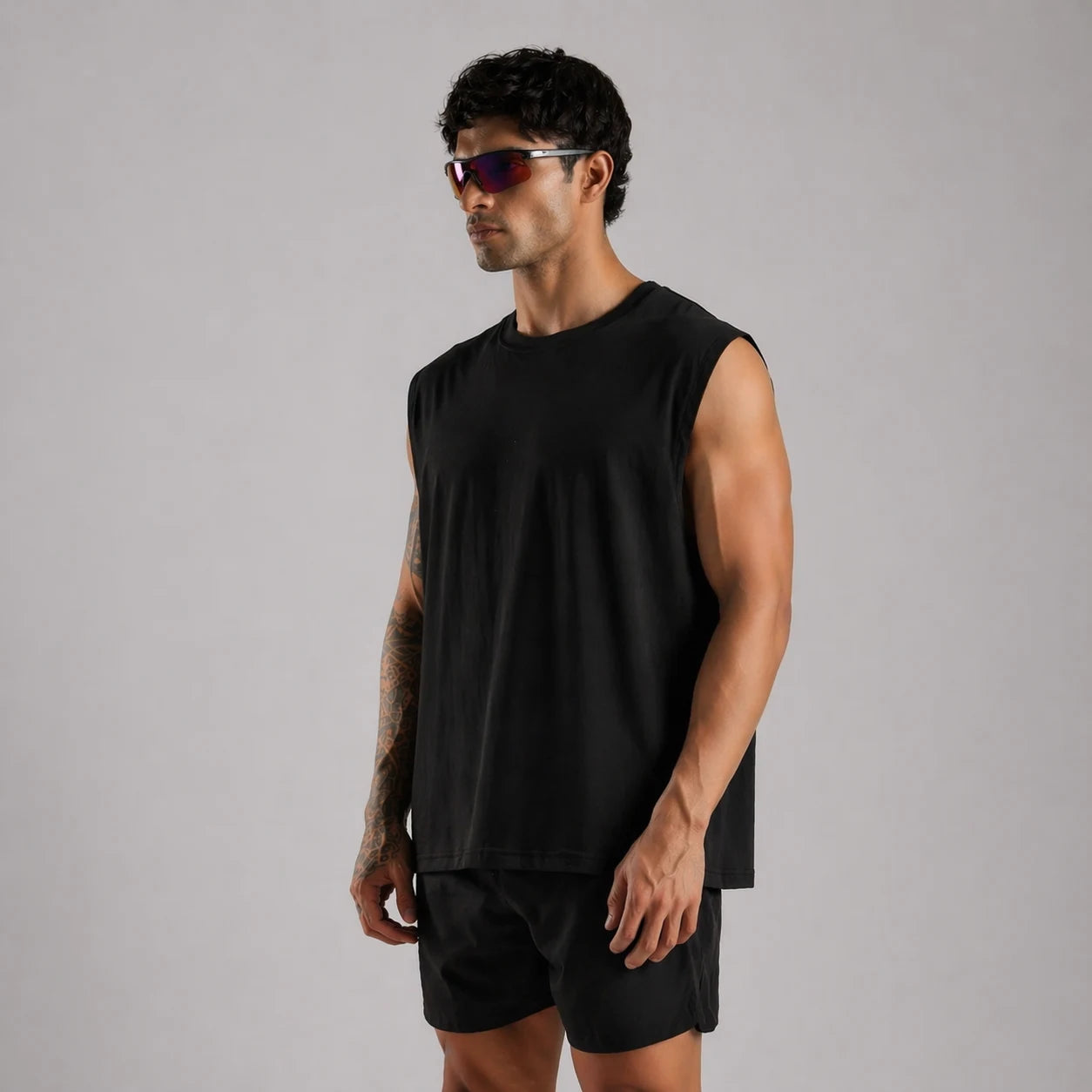 Man wearing a UNPROVEN black sleeveless OVERSIZE BOXY FIt , 240 GSM FRENCH TERRY COTTON and shorts on a gray background 