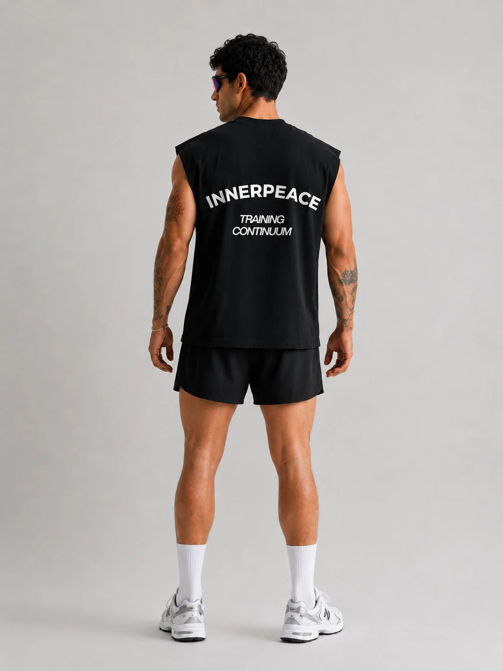 Person wearing a UNPROVEN black sleeveless Boxy fit with 'INNERPEACE TRAINING CONTINUUM' text on the back, standing against a plain background.
