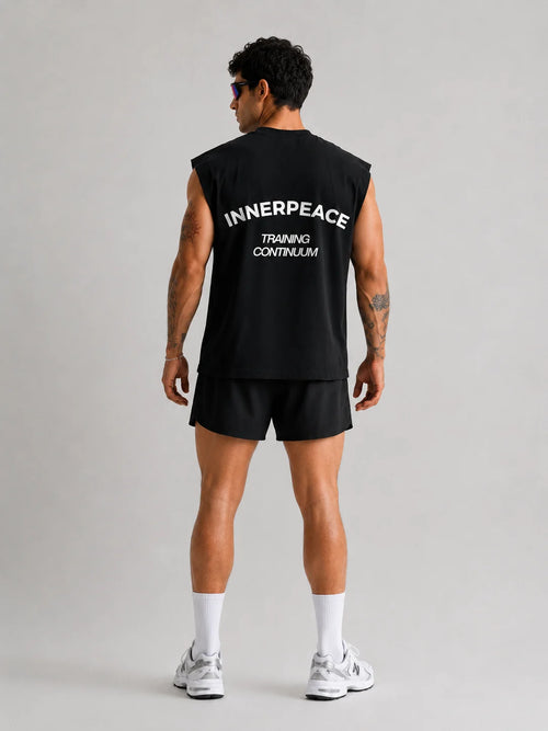Person wearing a UNPROVEN black sleeveless Boxy fit with 'INNERPEACE TRAINING CONTINUUM' text on the back, standing against a plain background.