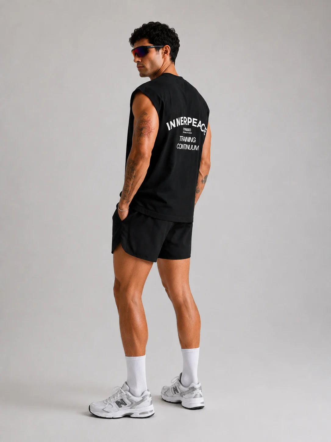 Person wearing a UNPROVEN black sleeveless OVERSIZE BOXY FIT TANK with 'INNERPEACE' Graphic design on the back, standing against a plain background.